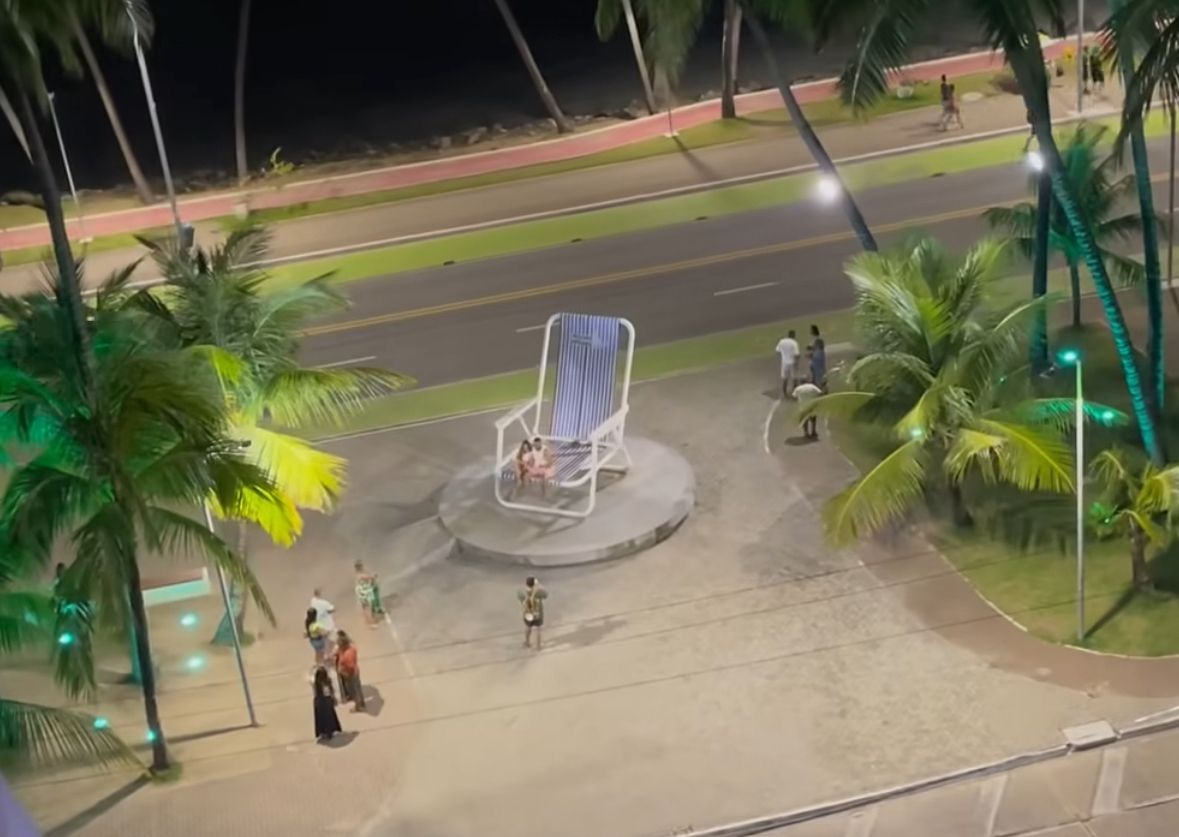 Turista usa escada para subir em cadeira gigante na praia